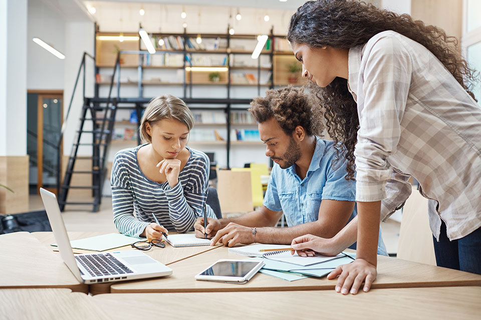 Group of three young multi-ethnic successful business people writing in a notepad