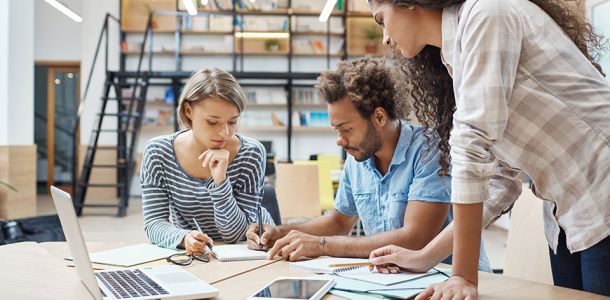 Group of three young multi-ethnic successful business people writing in a notepad