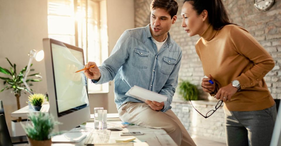 Young entrepreneur cooperating with female colleague while working on a computer in the office