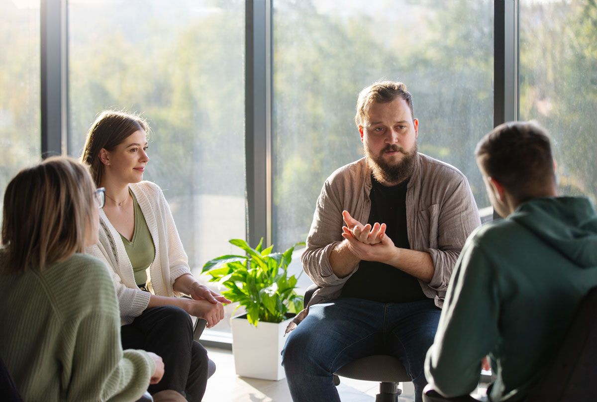 A group of people engaged in conversation while seated in a room.