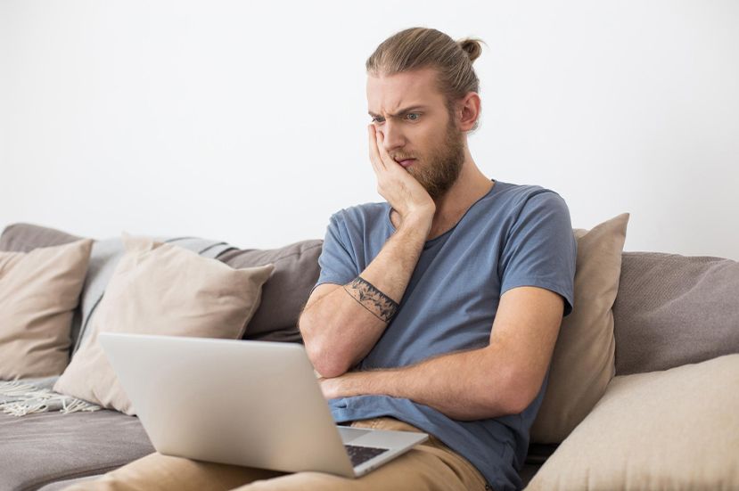 Man on laptop, annoyed with bad website