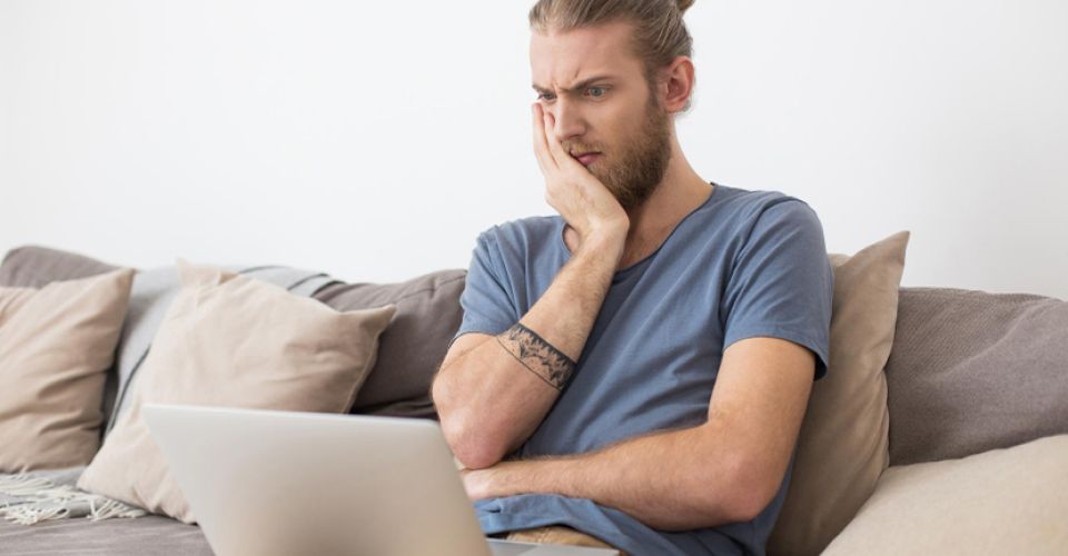 Man on laptop, annoyed with bad website
